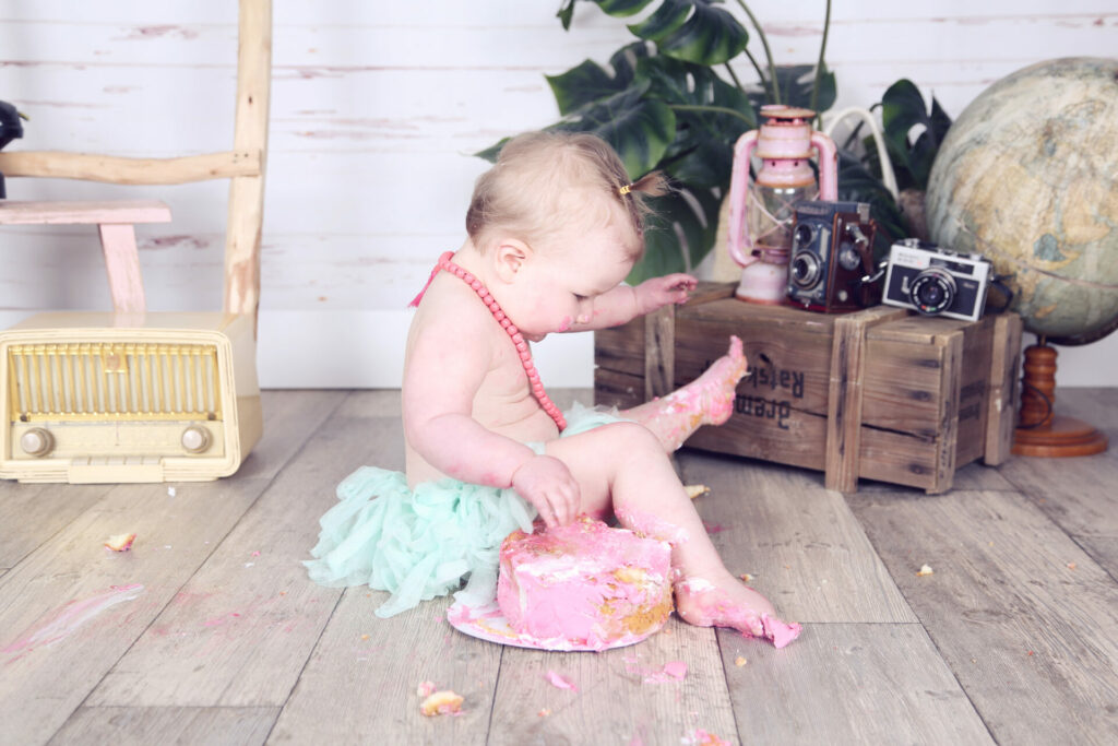 Baby met roze taart in een vintage studiodecor, cakesmash