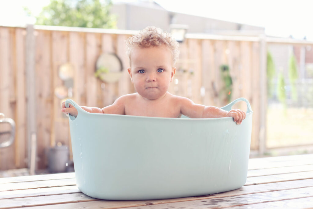 Baby in een mintgroene teil buiten, aankondiging van een eerste verjaardag