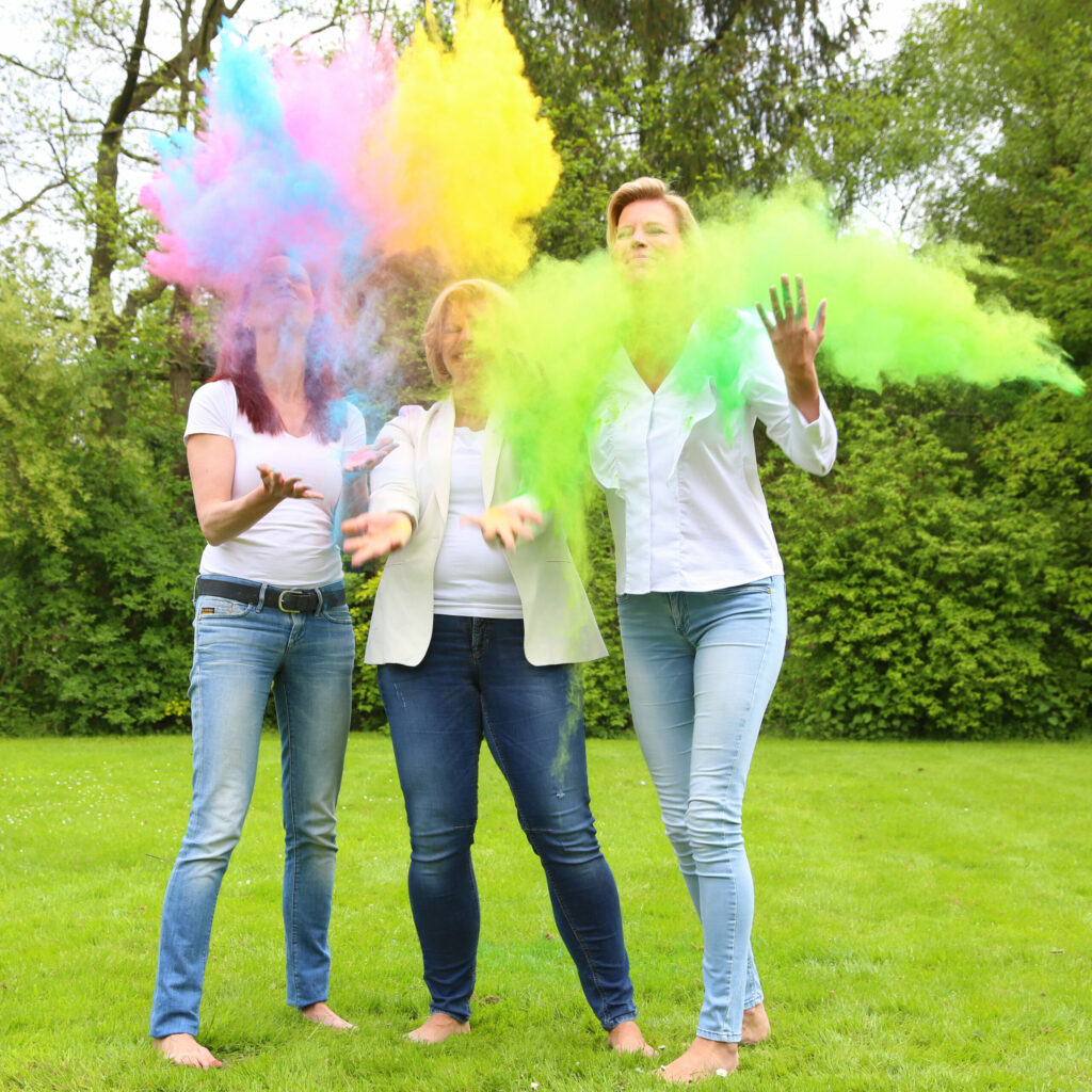 Vrouwen staan in een kleurrijke poederwolk in een tuin