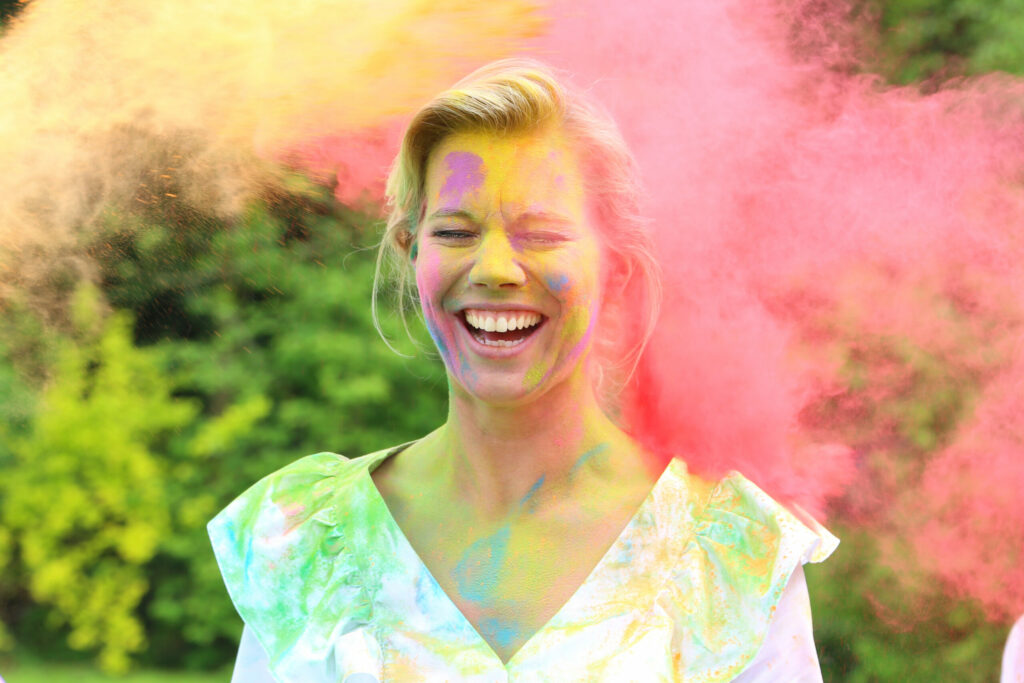 Vrouw lacht met roze poeder achter zich tijdens een ColorPowder-shoot