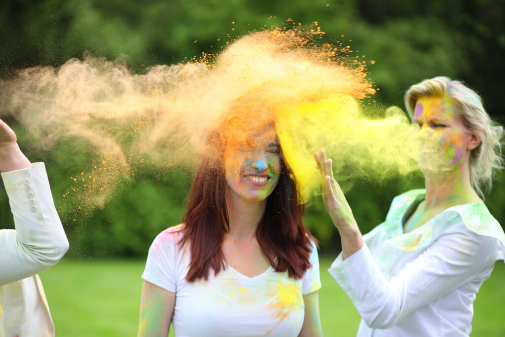 Vrouw gooit geel poeder over haar vriendin, ColorPowder-fotoshoot