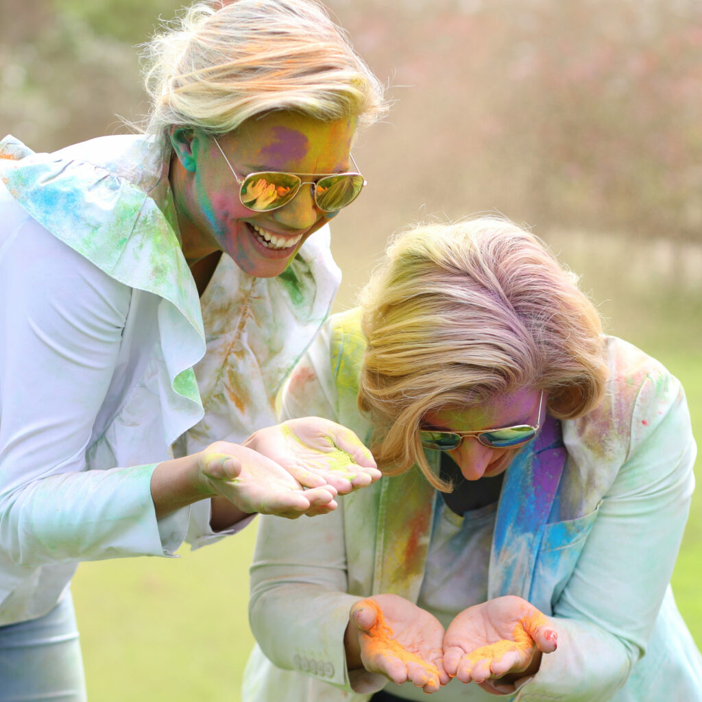 Twee vrouwen met spiegelende zonnebrillen en kleurenpoeder in de handen