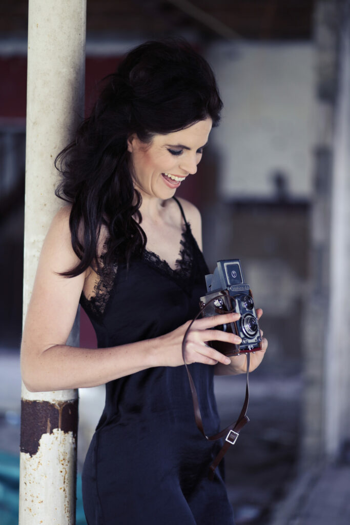 Vrouw met een vintage camera in een zwarte jurk, modelportret