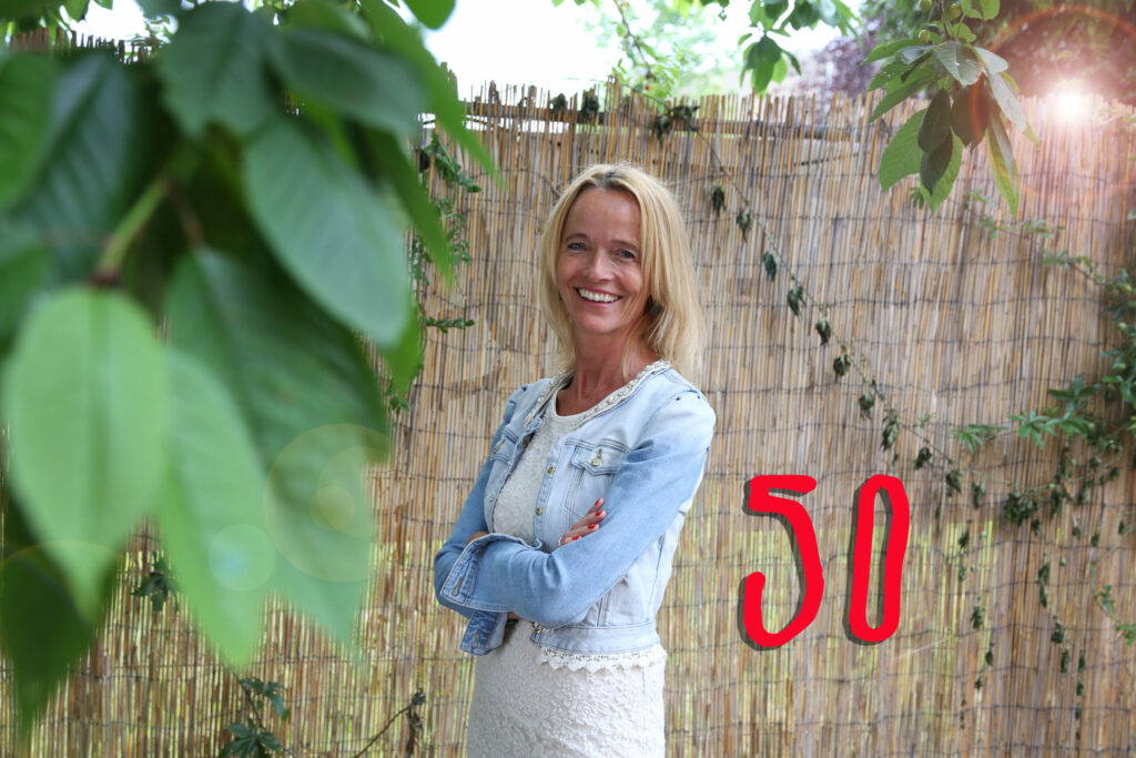Lachende vrouw bij een bord met '50' voor een verjaardagsaankondiging