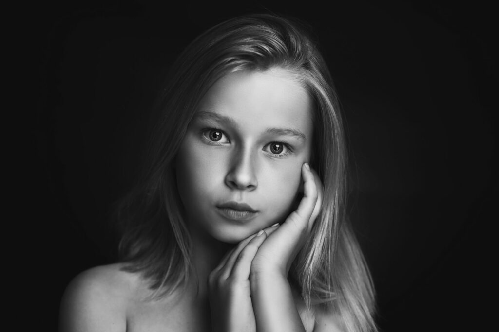 Zwart-witportret van een meisje met hand aan haar gezicht