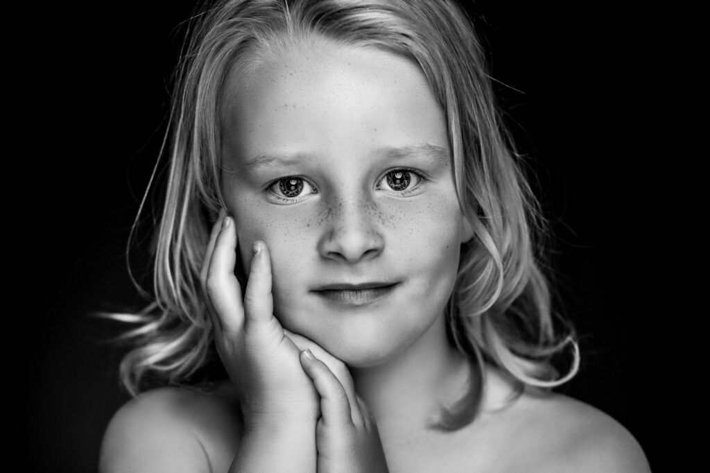 Zwart-witportret van een blonde jongen met de hand aan zijn gezicht