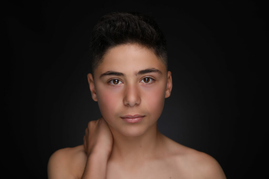 Tienerjongen met donker haar en hand bij zijn hals, Pure Portrait