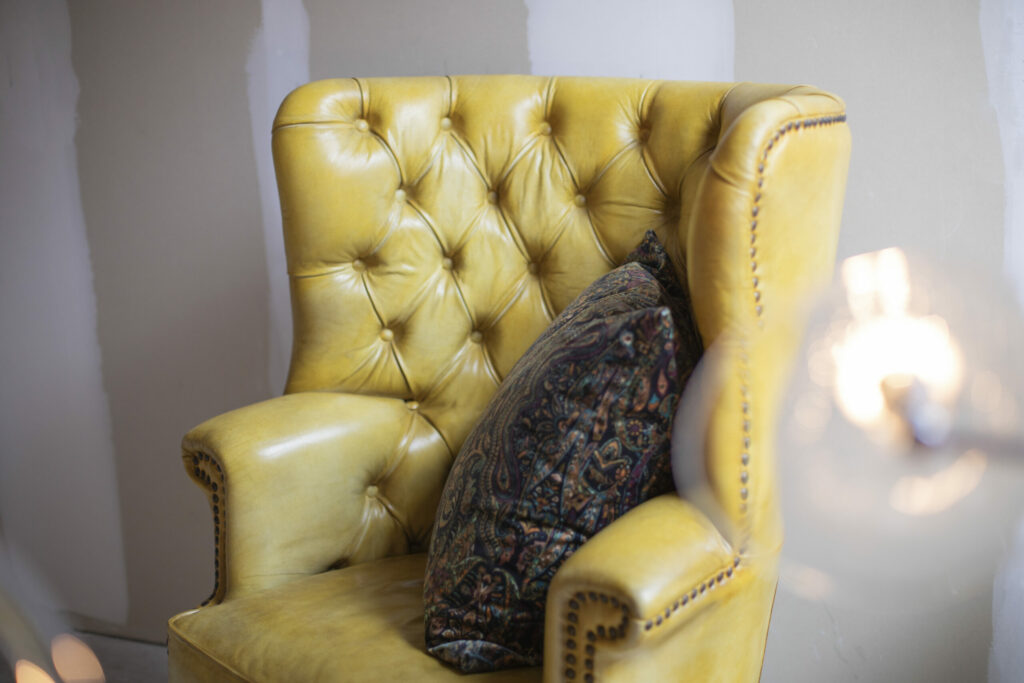 Gele chesterfield fauteuil met kussen en lampje, sfeerfotografie