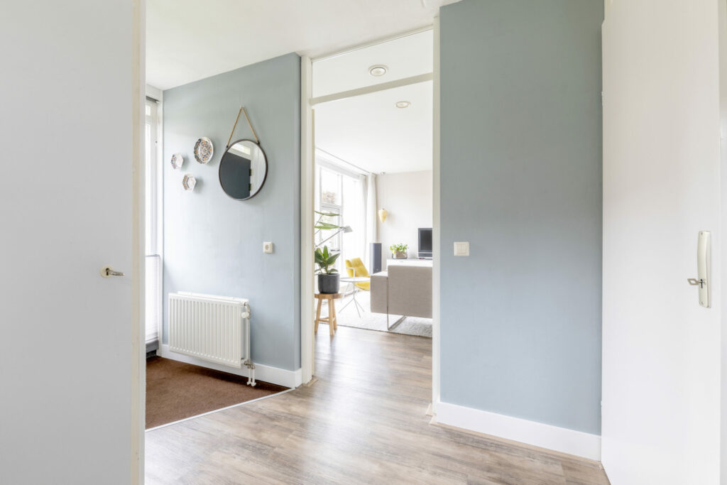 Doorkijk door een lichte hal naar de woonkamer, vastgoedfotografie