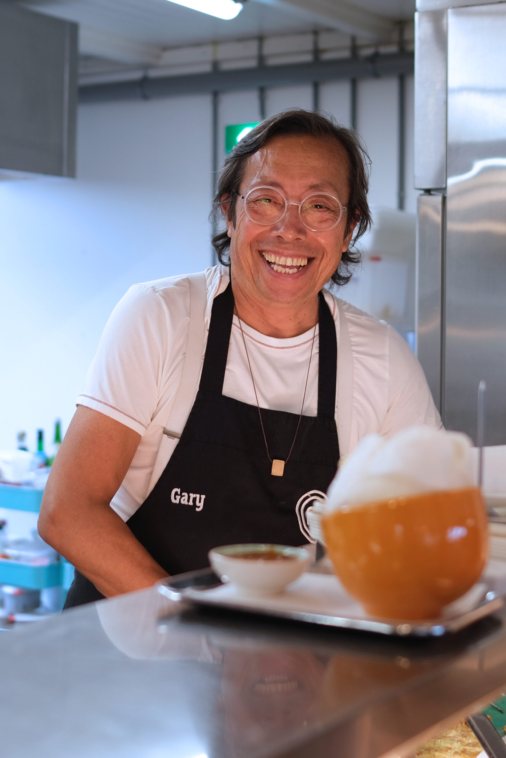 Barista met schort achter de bar met een koffie, zakelijk portret