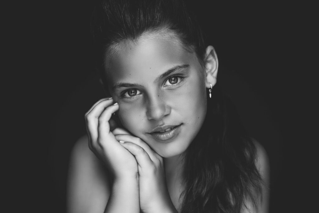 Zwart-witportret van een meisje met de hand aan haar wang