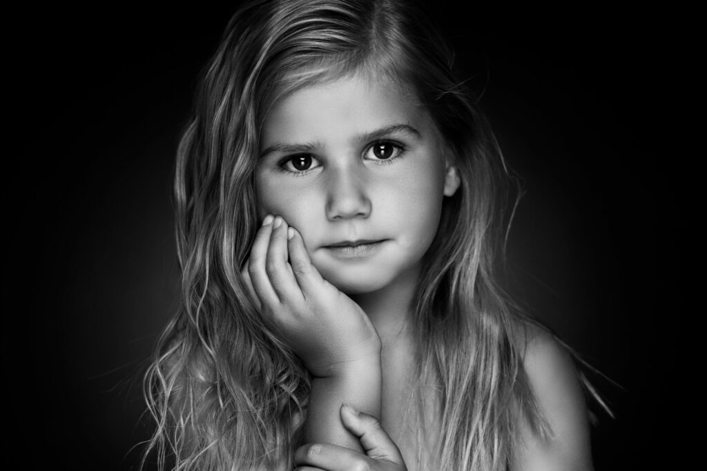 Zwart-witportret van een meisje met lang haar en hand aan de kin