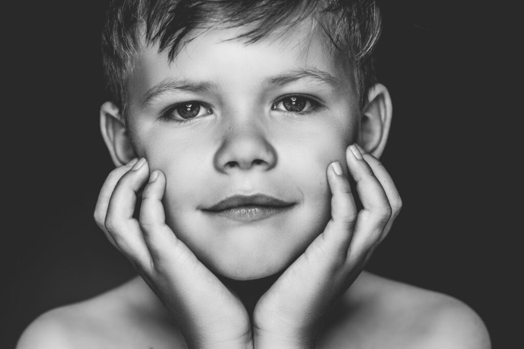 Zwart-witportret van een jongen met de handen aan zijn wangen