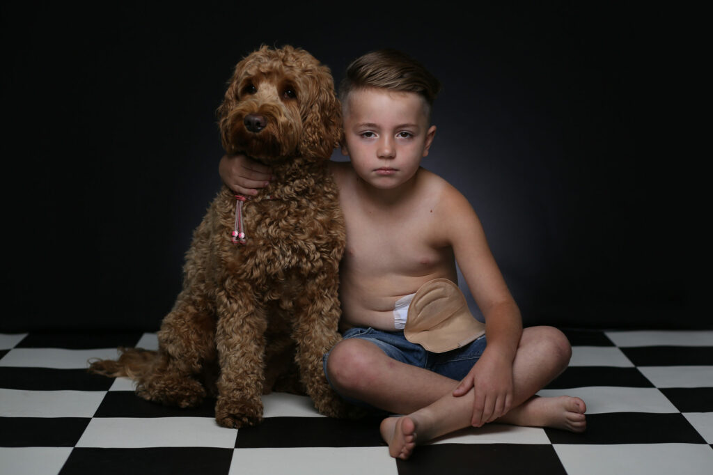 Jongen met een grote krullende hond op een geblokte vloer, dierenfotografie