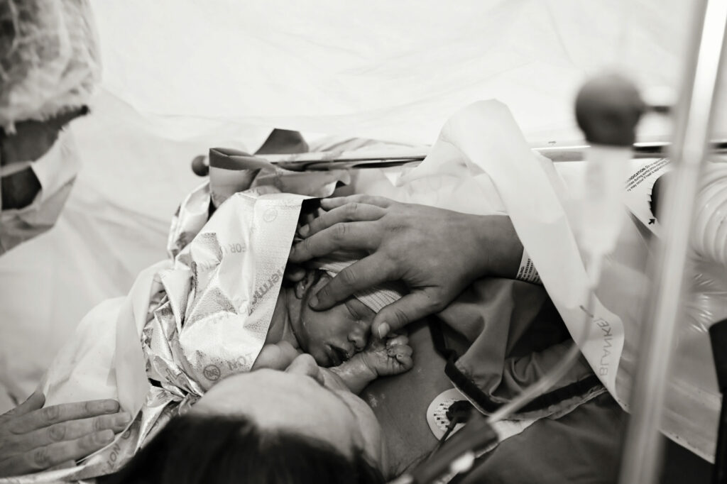 Zwart-witfoto van de baby kort na de geboorte op de borst van moeder