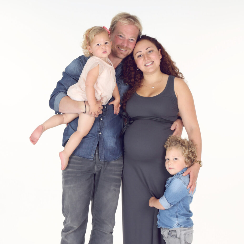 Zwangere moeder met gezin en twee kinderen in de witte studio