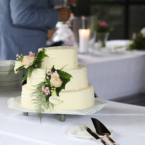 Witte bruidstaart met rozen en taartschep op tafel