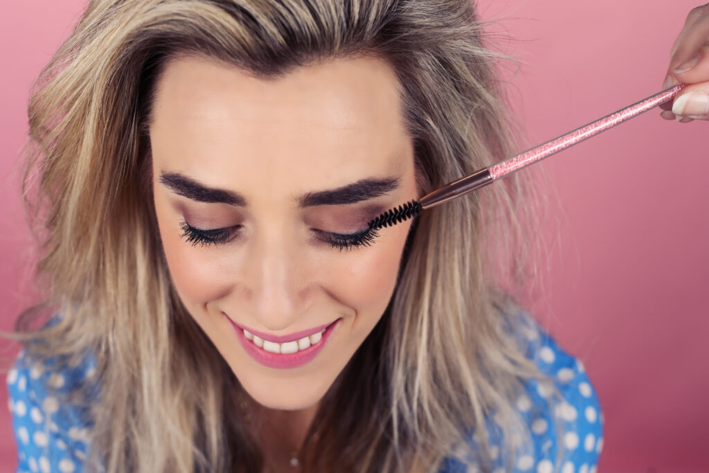 Visagiste brengt mascara aan bij een lachende vrouw, social media content