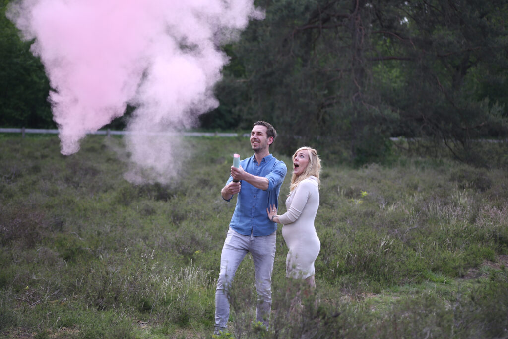 Stel bij een roze rookbom tijdens een gender reveal-fotoshoot buiten