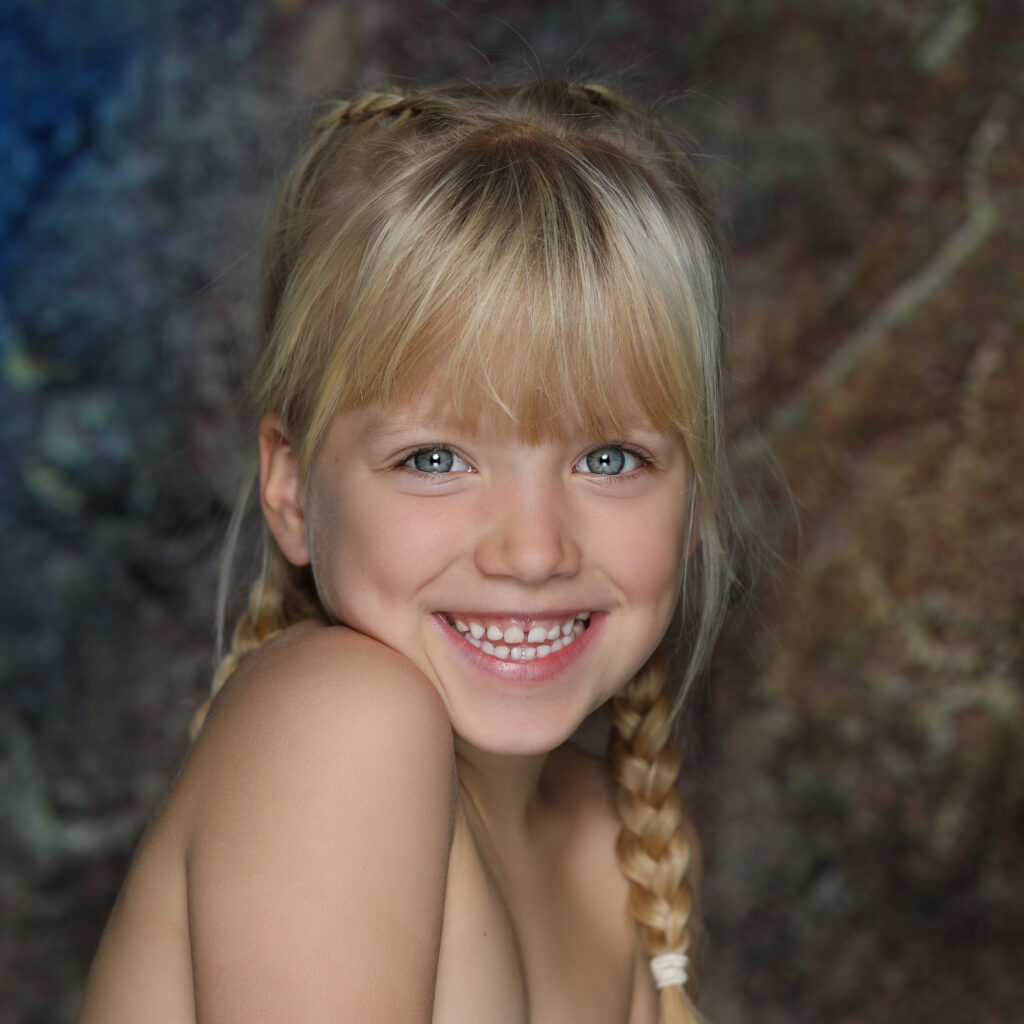 Schilderachtig portret van een lachend meisje met blonde vlecht