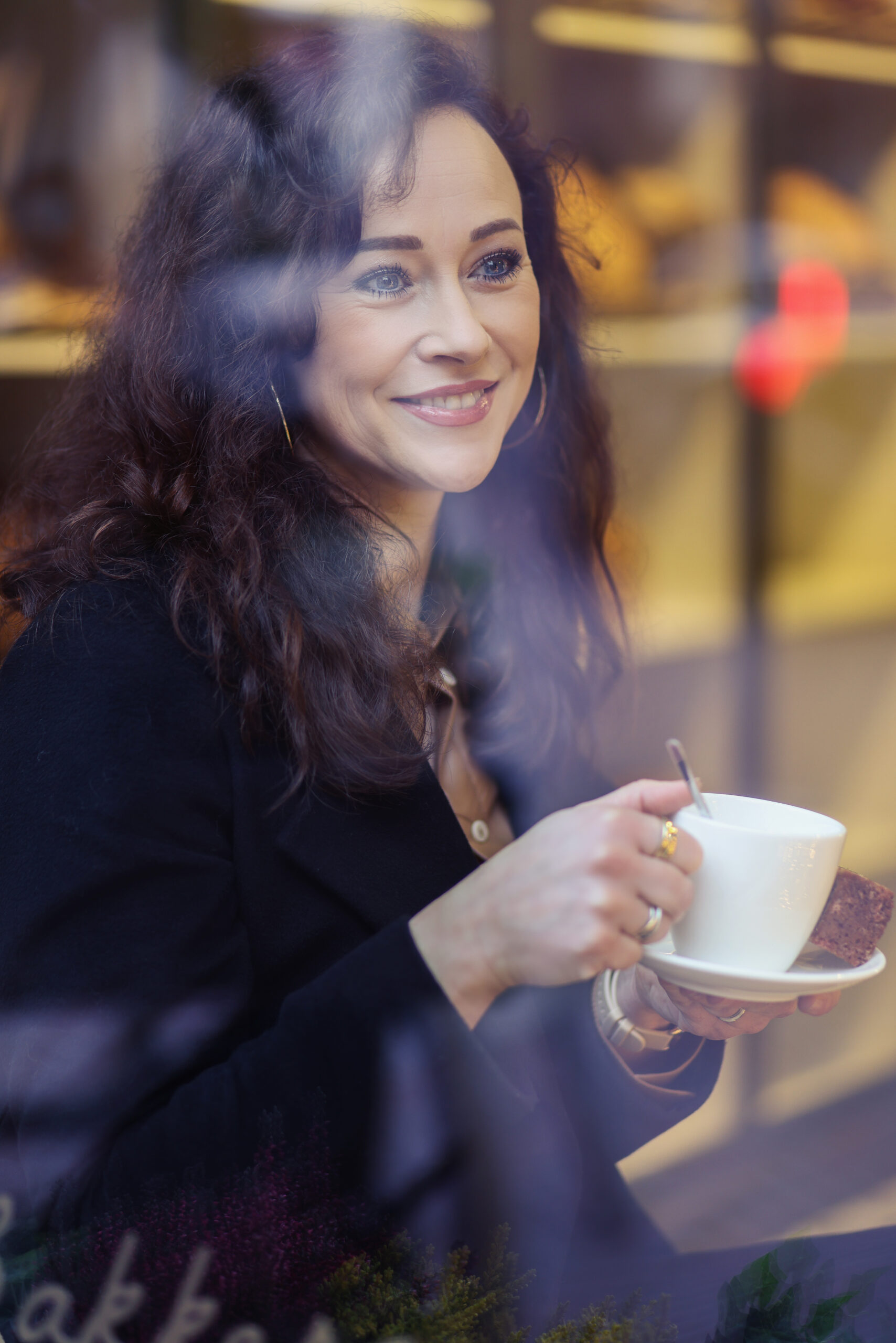 Zakelijk portret van een lachende vrouw met kopje koffie bij het raam