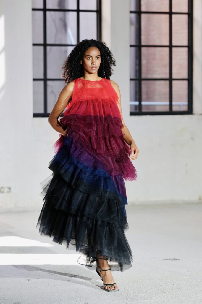 Model in gelaagde rood-blauwe tuljurk, modefotografie in een fabriekshal