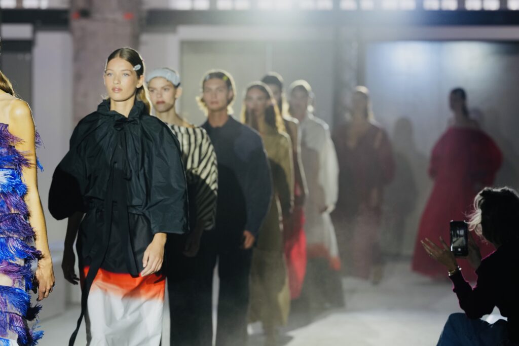 Groep modellen op de catwalk met fotografen ervoor, modeshow