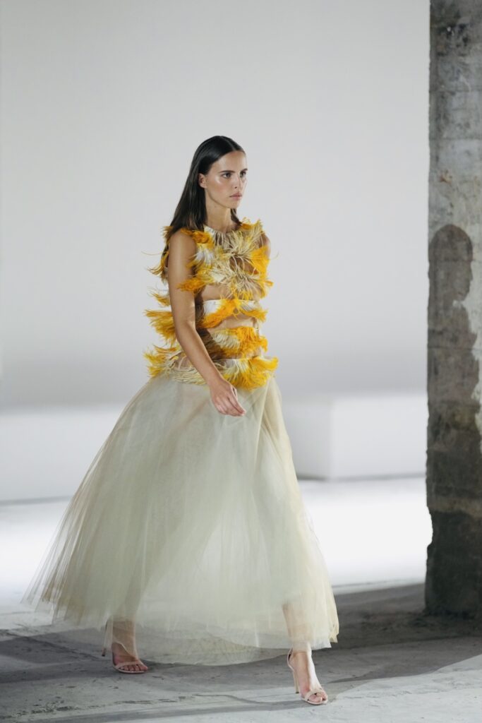 Model in tuljurk met gele bloemen op de catwalk