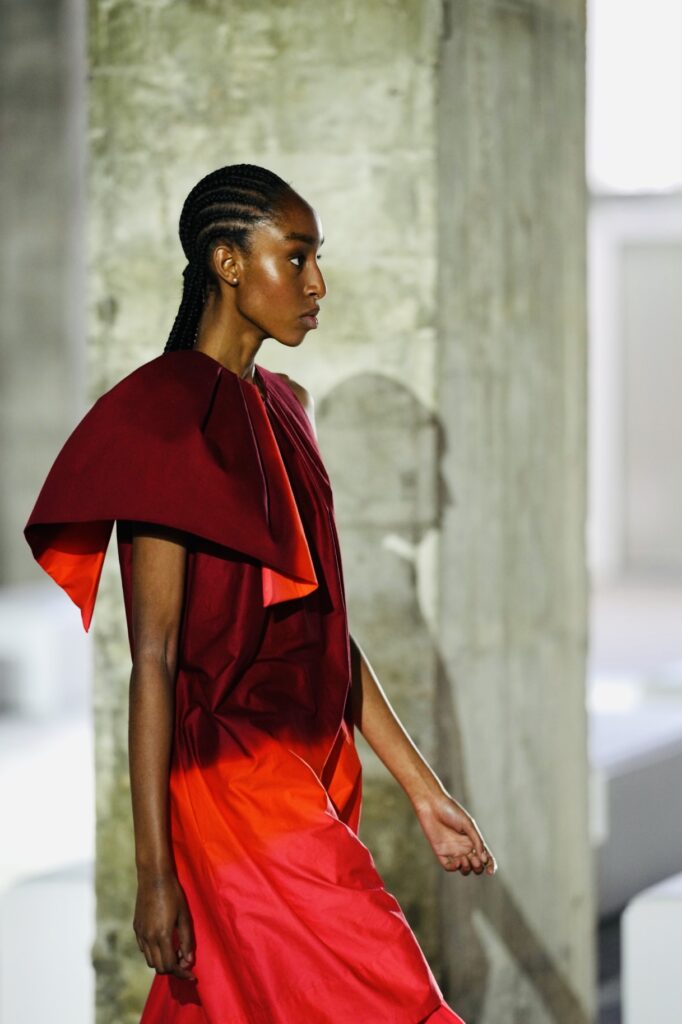 Model in rode jurk met grote kraag, modefotografie op de catwalk
