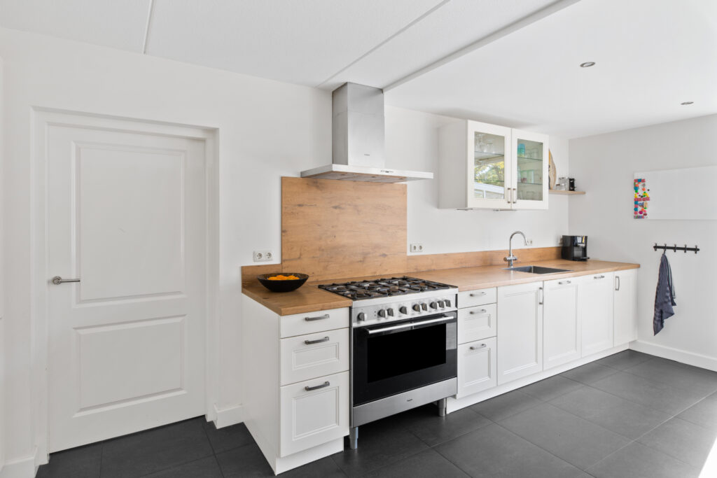Witte keuken met houten werkblad en RVS fornuis, vastgoedfoto