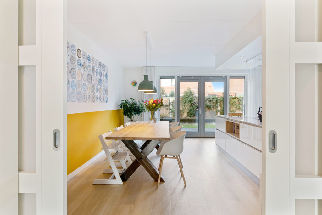 Eethoek met gele wand gezien vanuit de hal, woningfoto