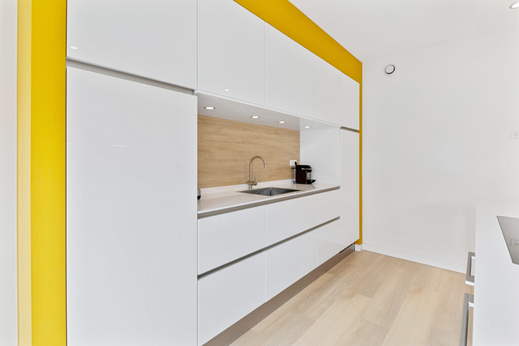 Witte keukenwand met gele accenten en houten werkblad
