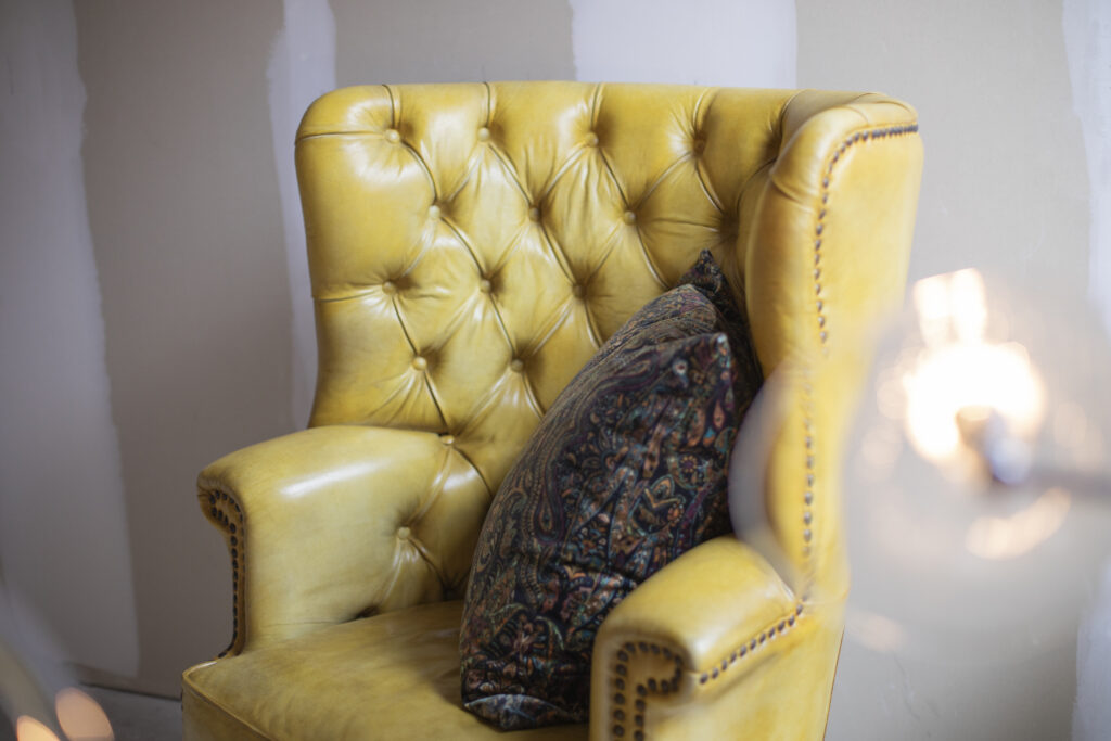 Gele chesterfield fauteuil met kussen bij het raam