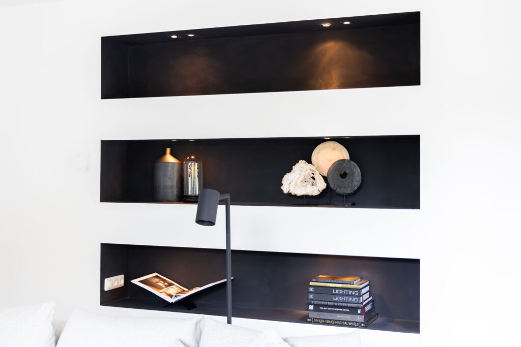 Witte wand met zwarte nissen vol decoratie, interieurdetail