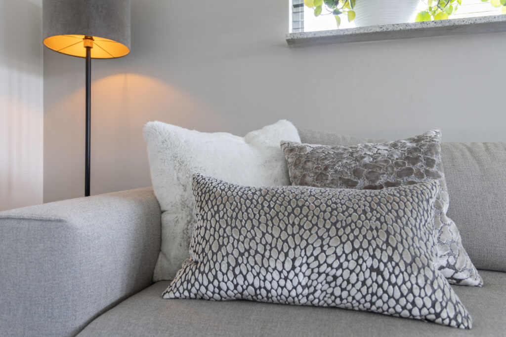 Grijze bank met panterprint kussens en staande lamp
