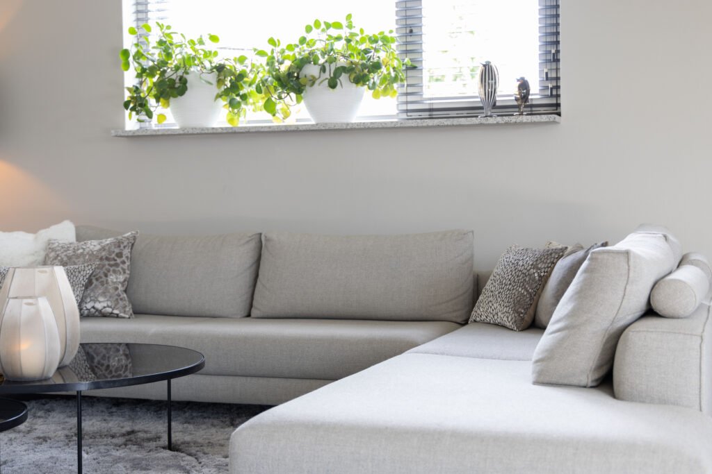 Lichte hoekbank in een moderne woonkamer met grote ramen