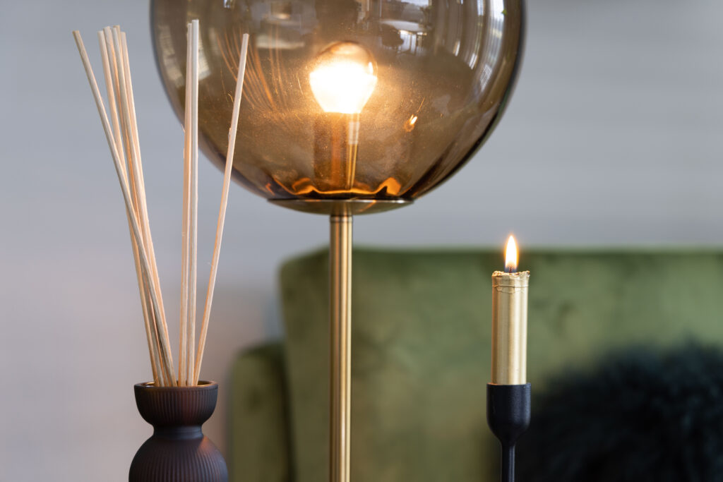 Gouden staande lamp en kaarsje in een sfeervolle woonkamer