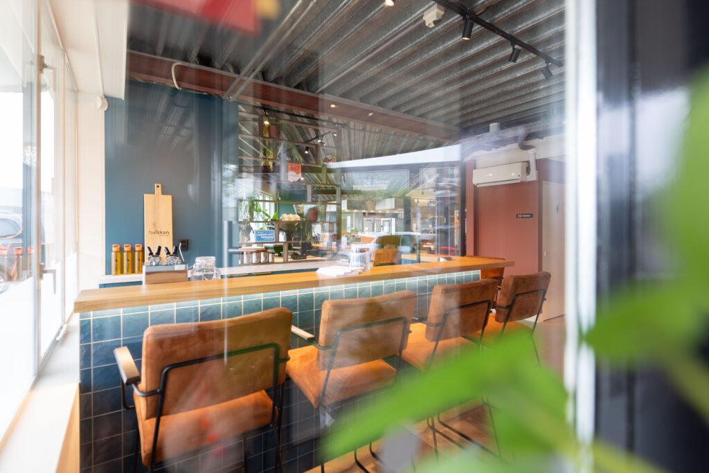 Lange houten bar met oranje stoelen in een industrieel interieur