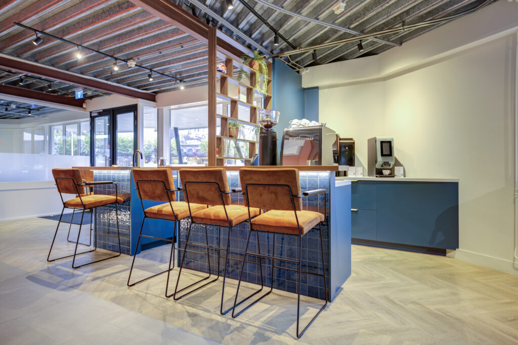 Industriële bar met oranje barkrukken en blauwe wand, bedrijfsinterieur