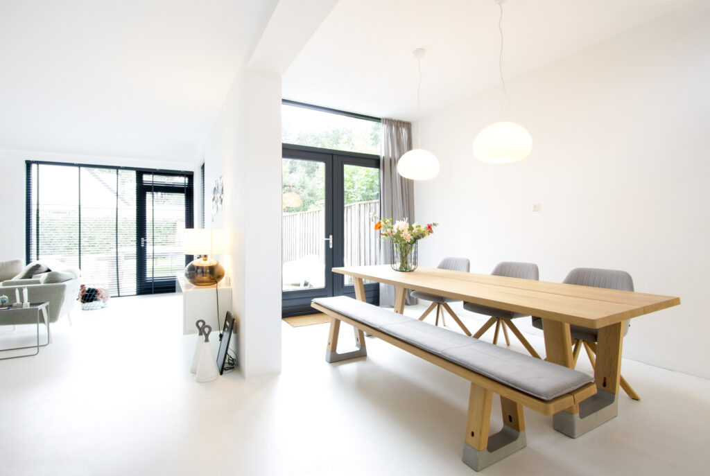 Lichte eetkamer met lange houten tafel en bank, woningfoto