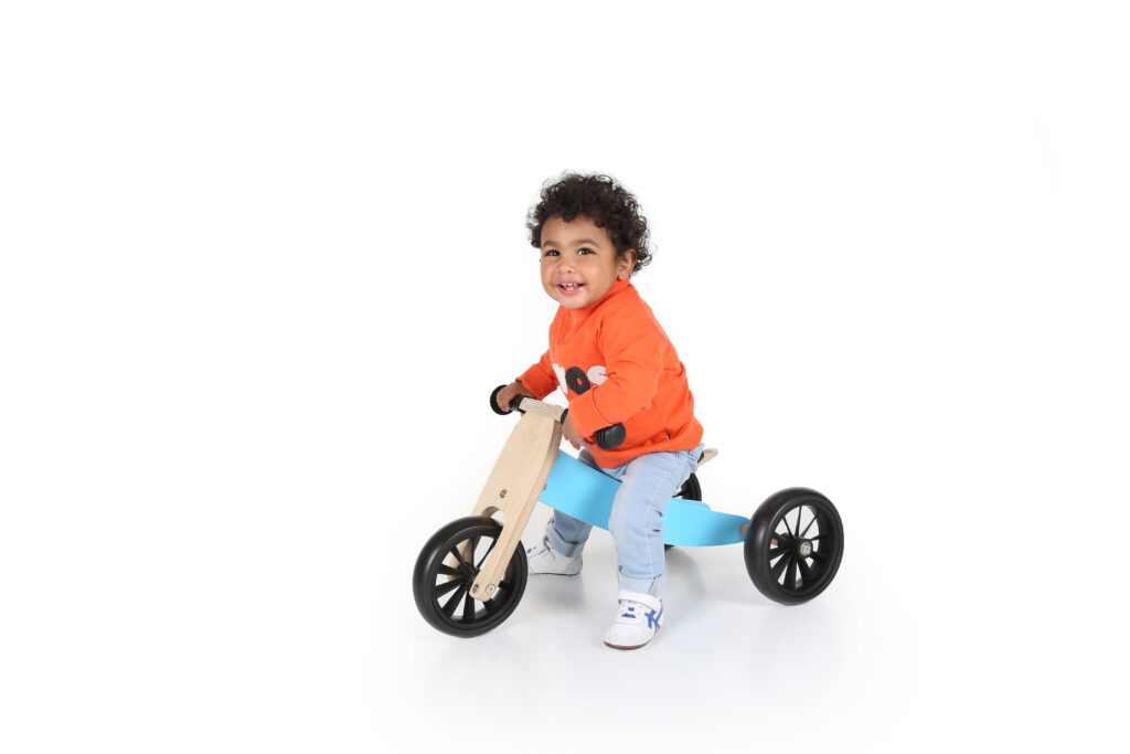 Jongetje op een houten loopfiets in de witte studio, productfoto