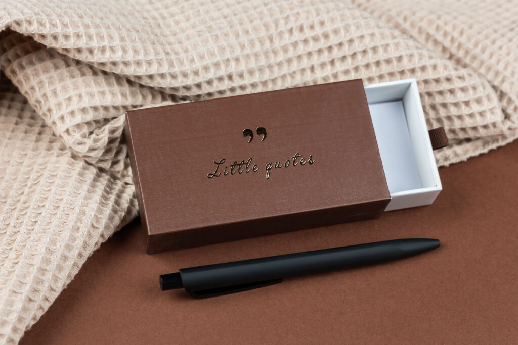 Bruine geschenkdoos met pen op een gebreide doek, packshot