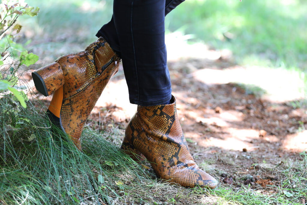 Bruine slangenprint laarzen in het gras, schoenenfotografie
