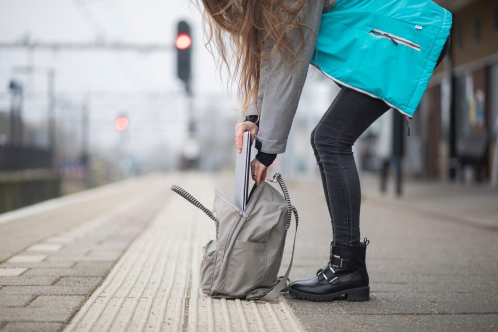 Vrouw opent een rugzak op een treinperron, lifestyle productfoto