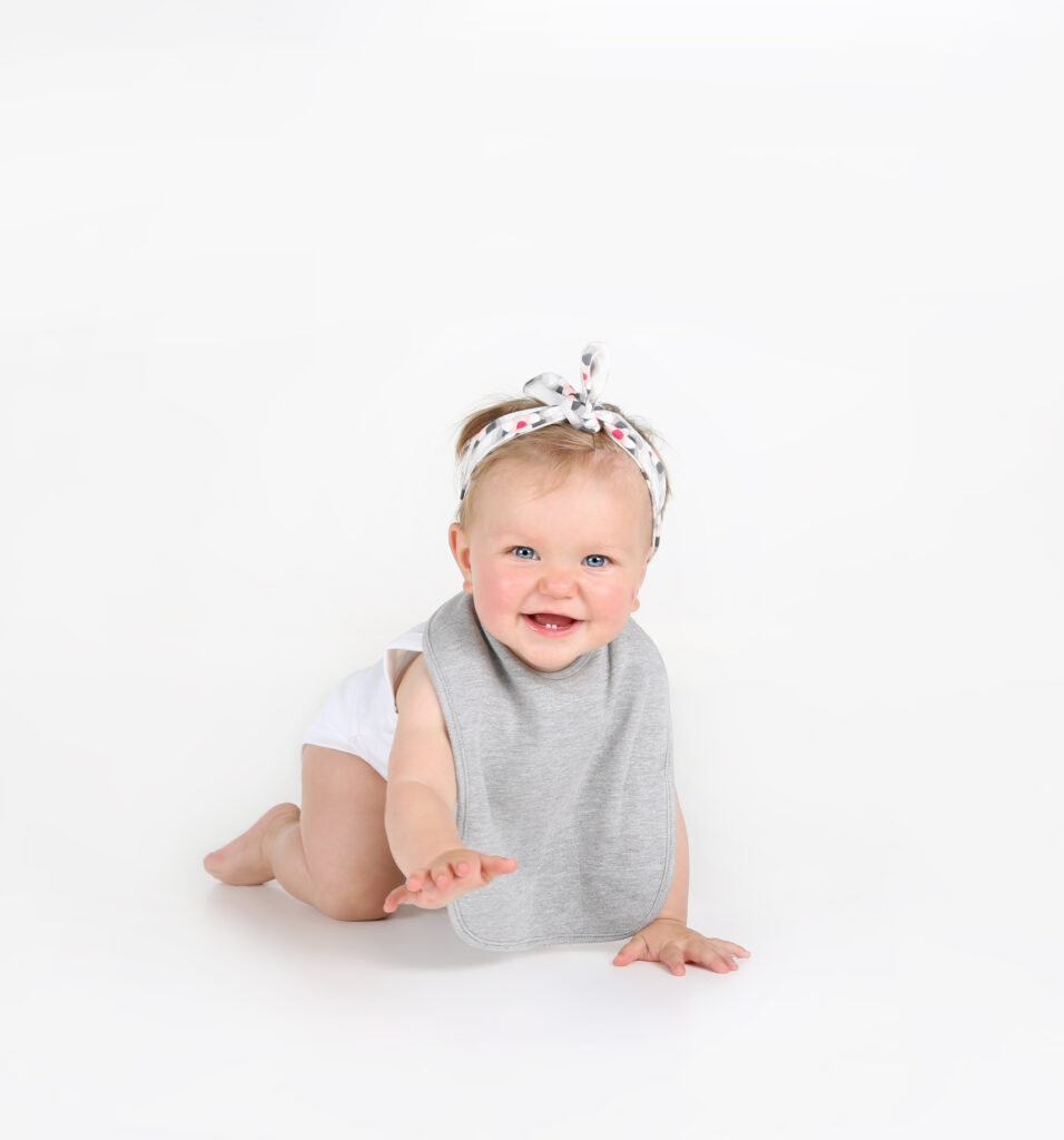 Lachende baby met haarband kruipt in de witte studio