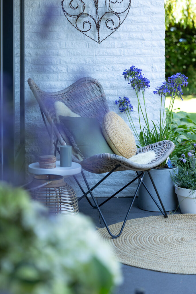 Vlinderstoel op een terras met blauwe bloemen, vastgoedfotografie